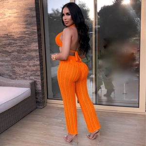 Side view of vibrant orange crochet two-piece set featuring halter top and trousers