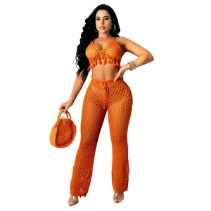 Detailed knit texture of bright orange crochet crop top with fringe and mesh hollow pants