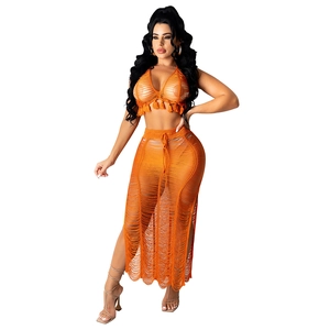 Detail of orange knit beach set featuring fringe crop top and side slit maxi skirt