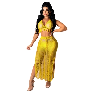Detail of yellow crochet knit two-piece set with fringe hem top and side slit maxi skirt