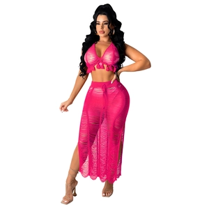 Detail of hot pink crochet beach set featuring fringe crop top and shredded side slit skirt