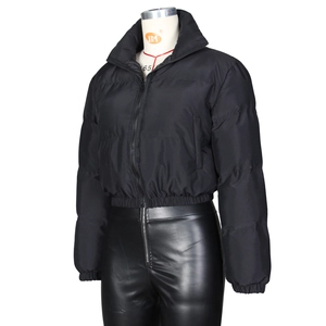 Detailansicht der schwarzen Damen-Pufferjacke und glänzenden Lederhose mit hohem Bund