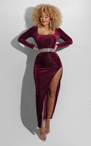 Detail of burgundy velvet evening dress featuring a crystal waist belt and high side slit