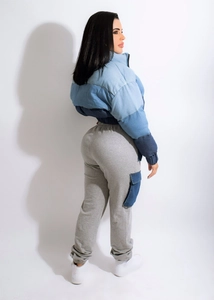Detail shot of a blue patchwork quilted jacket and grey joggers with denim side pockets