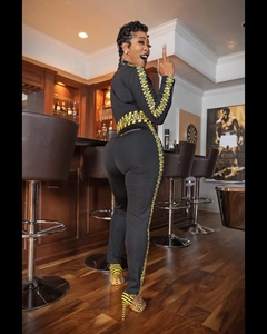 Detail of yellow CAUTION tape on black sports outfit with slim fit and zipper neck