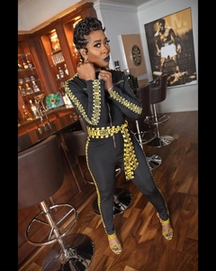 Close-up of black jumpsuit featuring CAUTION GRITTY GIRL yellow lettered tape detail