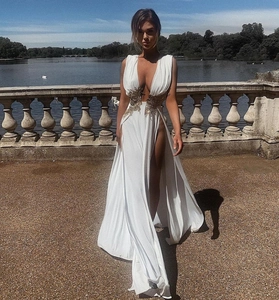 Détail de robe de soirée blanche à col en V profond avec broderie florale dorée à la taille