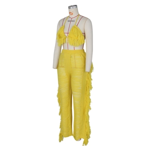 Detail von gelbem Strickset mit Neckholder-Fransentop und ausgestellter Hose im Lochmuster