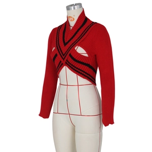 Detail of red knit cropped sweater featuring black striped trim and ribbed texture