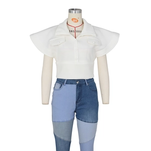 Detail of white winged-sleeve vest with lapel collar paired with two-tone patchwork jeans