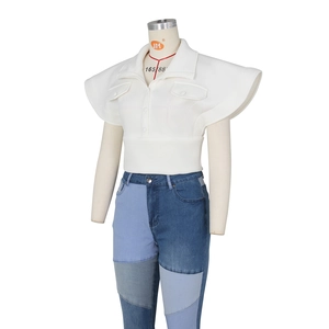 Detail view of white wing-sleeve top and multi-tone patchwork denim jeans on mannequin