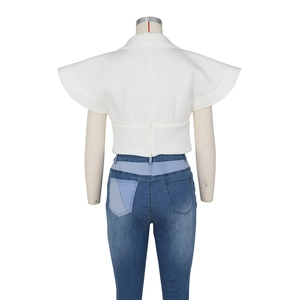 Detail view of white ruffle sleeve top and blue patchwork jeans on a mannequin