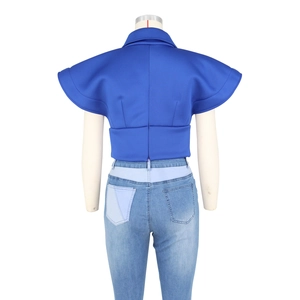 Detail view of royal blue crop top with structured back seams and mixed denim jeans