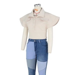 Close-up of beige stand-collar vest with flutter sleeves and patchwork denim jeans