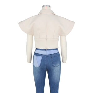 Rear view detail of off-white vest with flutter sleeves and paneled denim jeans