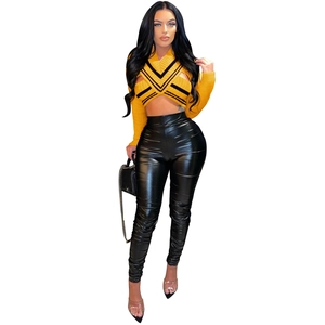 Front view of ginger yellow cross halter knit top paired with black high-waist faux leather pants