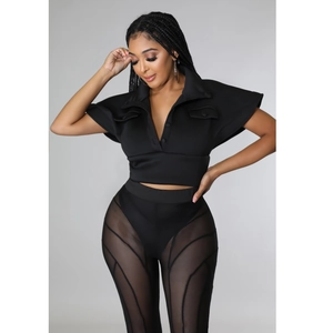 Detail of black V-neck crop top with button closure and mesh paneling trousers set