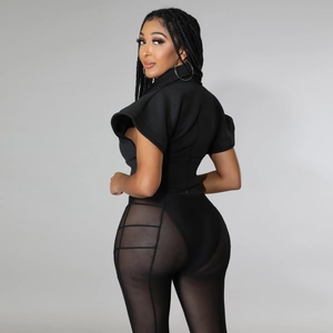 Detail view of black high-neck top with structured cap sleeves and mesh panel trousers