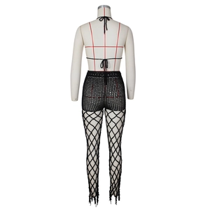 Rear view of black crochet knit beach set featuring cutout fishnet pants and halter top