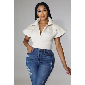Close-up of lapel collar and flap pockets on cream sleeveless top with button detail