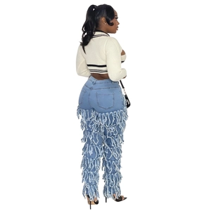 Detail view of denim jeans featuring layered fringe design and white striped knit sweater