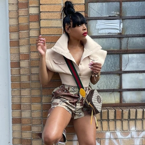 Detail of a chic beige stand collar sleeveless vest paired with camouflage shorts