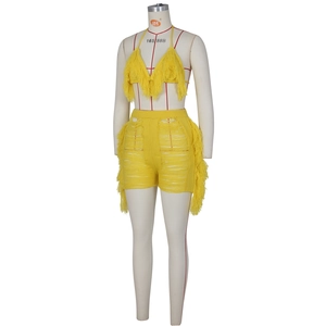 Détail de l'ensemble deux pièces en tricot jaune avec des pompons et un design ajouré chic