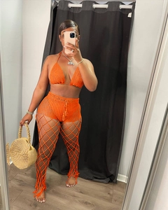 Detail view of orange crochet three-piece set with hollow knit trousers for beach vacation