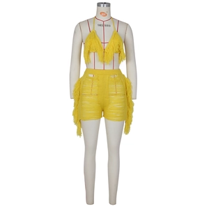 Détail d'un ensemble deux pièces en tricot jaune vif avec haut à franges et short ajouré