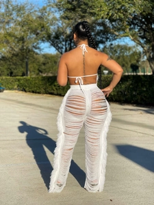 Rückansicht von weißem Neckholder-Top und High-Waist-Strickhose mit Fransen und Ausschnitten