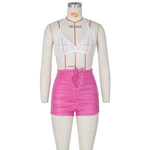 Detail of white crochet halter top and pink high-waisted pleated PU leather shorts