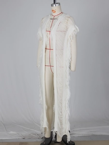 Gros plan détaillé du cardigan blanc en tricot avec franges bohèmes et motifs ajourés
