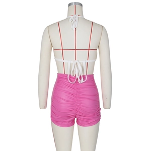 Detail view of pink high-waisted gathered PU shorts and white knitted halter top