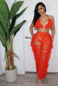 Detailansicht eines leuchtend orangefarbenen Stricksets mit langen Fransen-Quasten