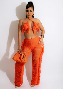 Detail eines hellorangen Strick-Zweiteilers mit Fransen-Bralette und Lochmuster-Hose