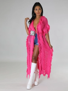 Détail d'un cardigan en maille fuchsia avec de longues franges et des éléments ajourés