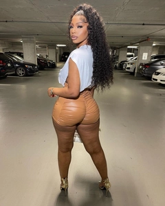 Close-up of brown high-waisted PU leather shorts with pleated back detail on a model