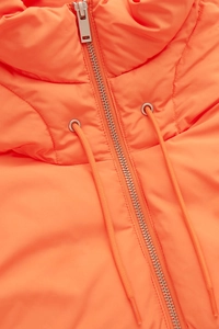 Gros plan détaillé du gilet matelassé orange vif avec fermeture éclair argentée
