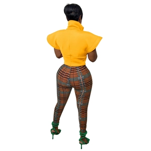 Rear view of ginger yellow stand collar vest with flutter sleeves and plaid trousers