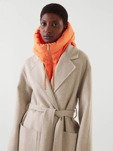 Détail d'un manteau en laine beige avec un faux col à capuche rembourré orange vif