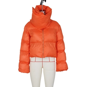 Detailed close-up of bright orange puffer jacket with high neck scarf design and zipper