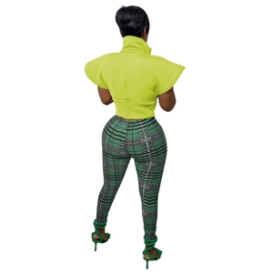 Rear view of woman wearing yellow ruffled sleeve top and green checkered trousers