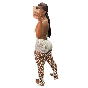 Detail of white crochet knit beach set with halter top and hollow out mesh trousers