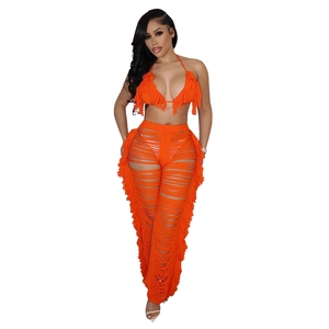 Detail eines leuchtend orangefarbenen Strick-Sets mit Fransenquasten und Cut-out-Design