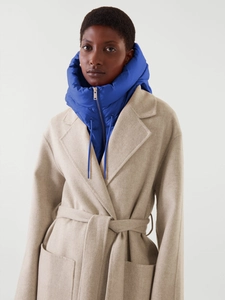 Détail d'un cache-cou à capuche bleu duvet porté avec un manteau en laine beige