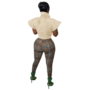 Back view of a chic beige high collar sleeveless top paired with plaid leggings