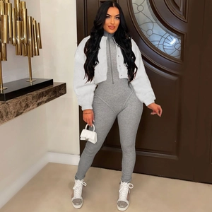 Detail of white faux fur jacket paired with a grey ribbed knit jumpsuit and trendy sneakers