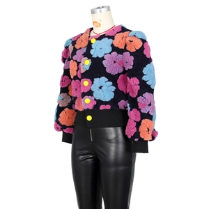 Detail view of plush textured jacket with colorful 3D floral motifs and yellow buttons