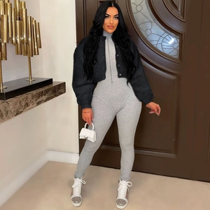 Detail of grey ribbed turtleneck jumpsuit paired with a black cropped button jacket