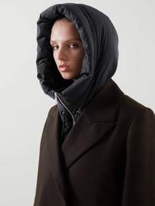 Détail d'une capuche noire matelassée avec fermeture éclair sur un manteau de laine brun